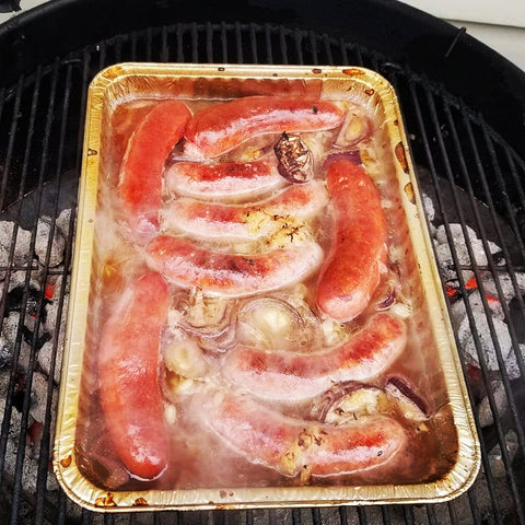 Brats soaking in beer on grill