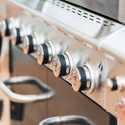 Close-up of grill temperature control knobs and built-in thermometer